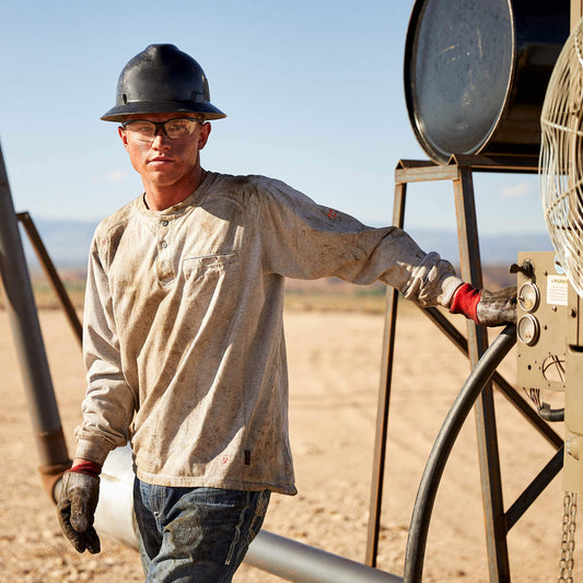 Man in work attire standing next to industrial equipment in a desert setting