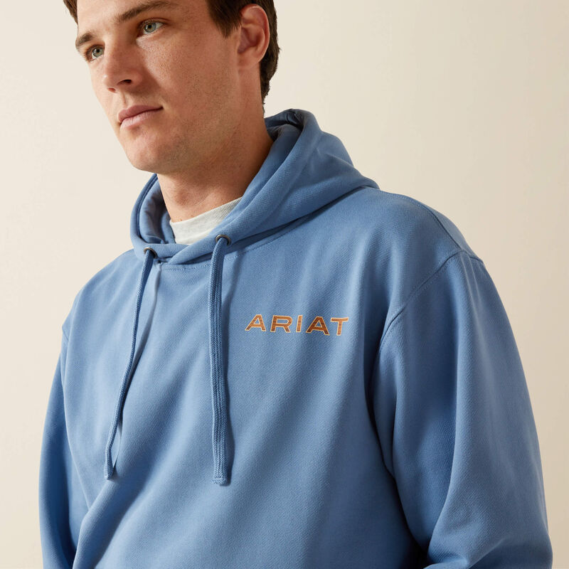 Man wearing light blue ARIAT hoodie with drawstrings, casual outfit, neutral background