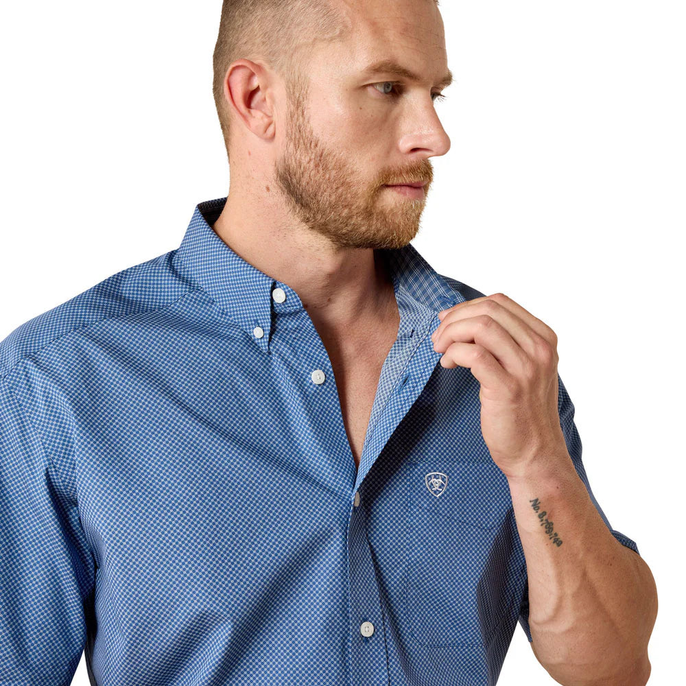 Man wearing a blue checkered shirt with a visible brand logo on a white background