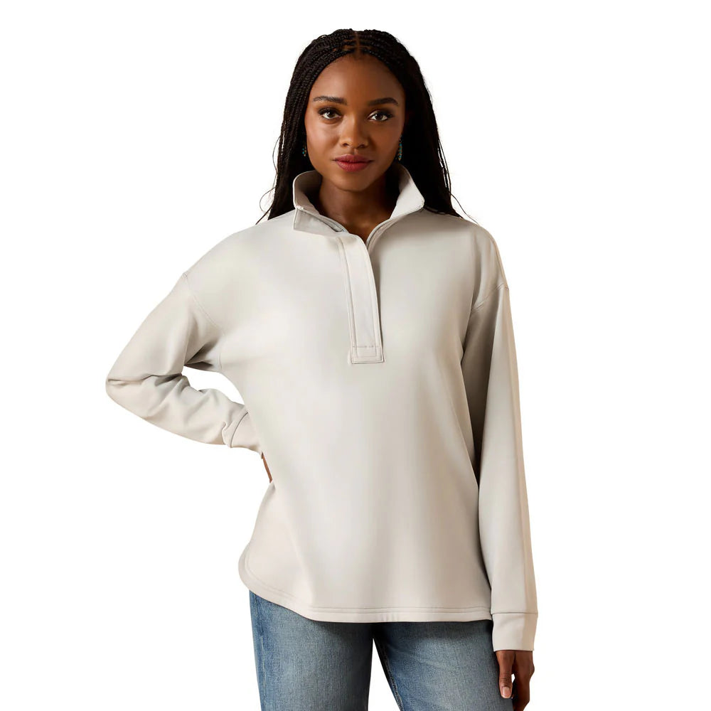 Woman wearing a beige pullover sweatshirt with high collar and blue jeans