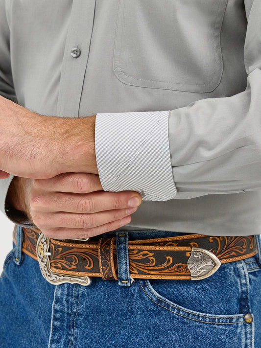 Man wearing gray dress shirt, patterned cuff, tooled leather western belt, blue jeans