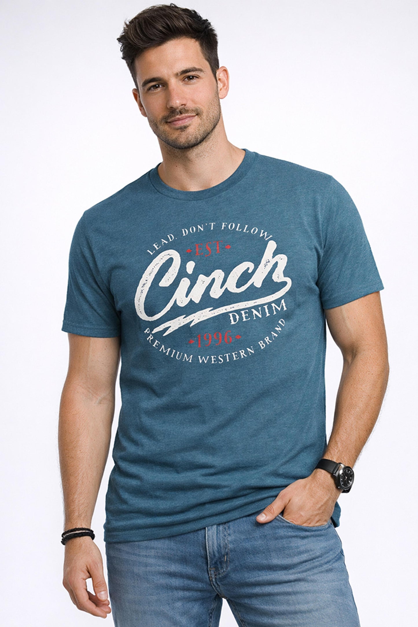 Man wearing teal graphic tee with Cinch Denim 1996 western logo, blue jeans, casual style