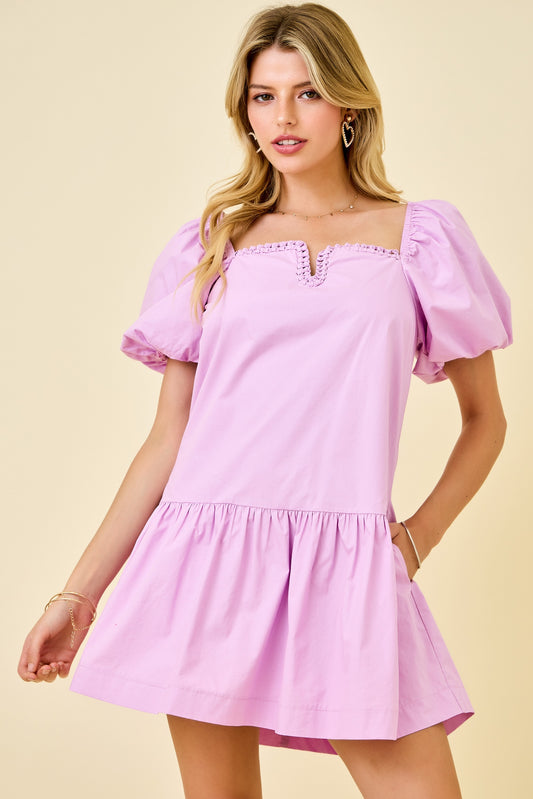 Woman wearing a pink dress with puff sleeves against a beige background