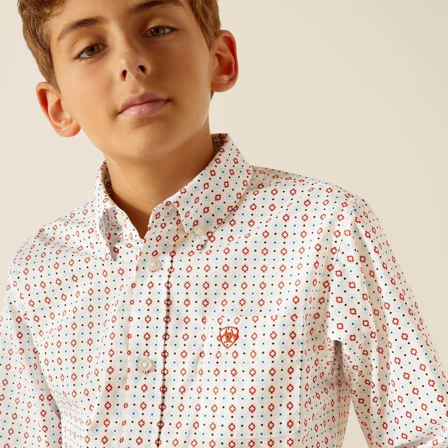 Boy in a white button-up shirt with red and blue geometric print and front pocket
