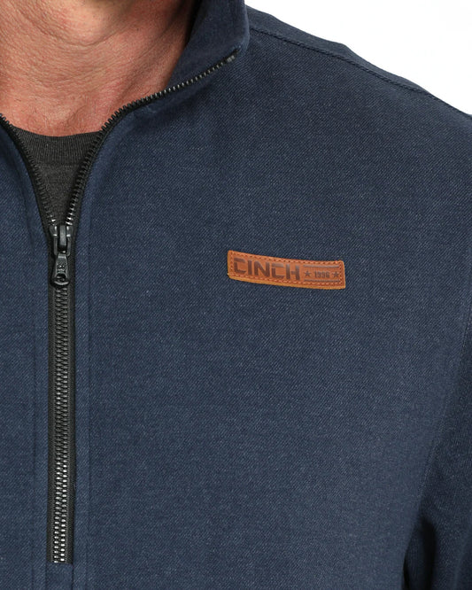 Close-up of a navy zip-up jacket with CINCH logo patch on chest