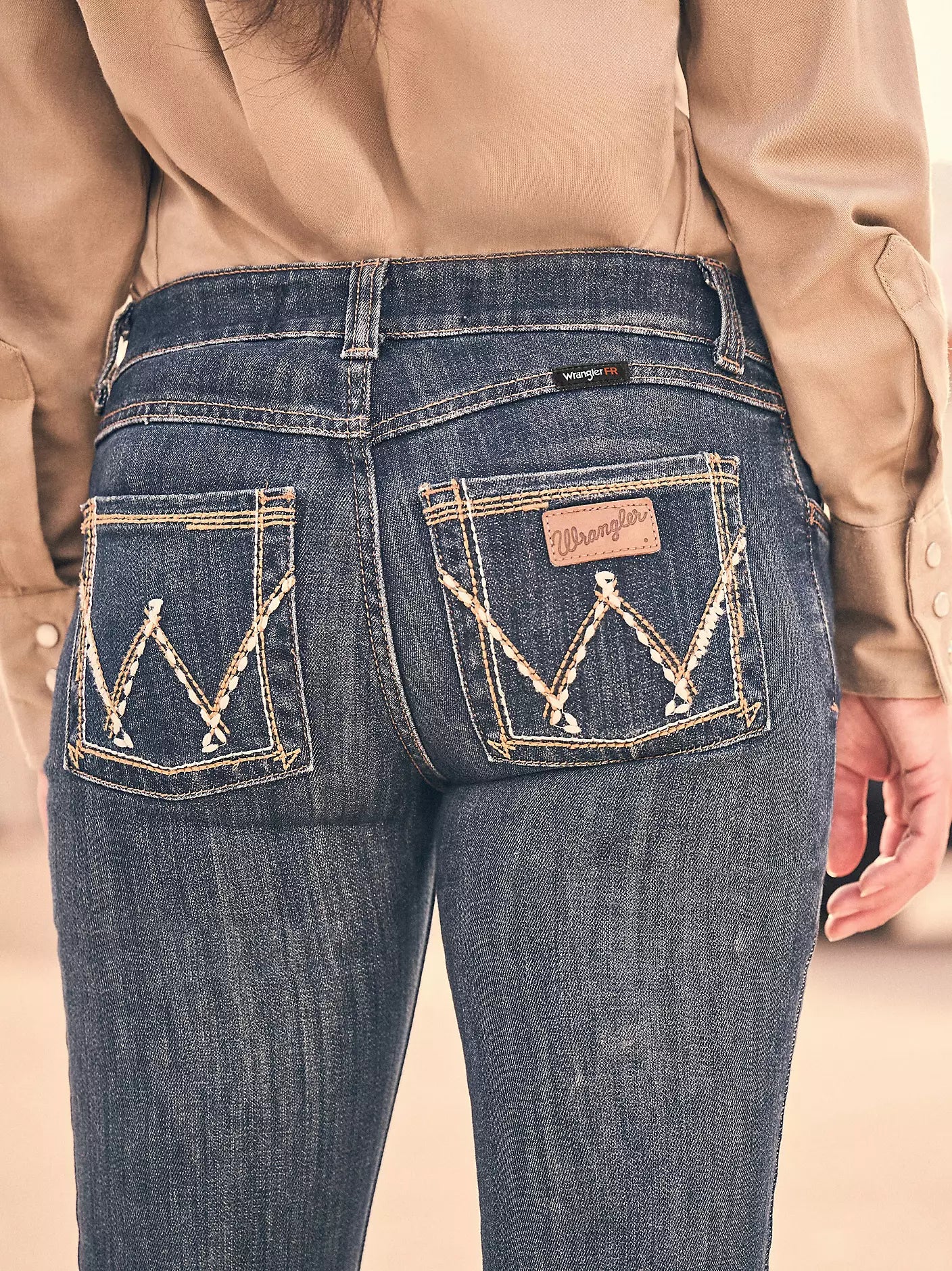 Close-up of woman wearing blue Wrangler FR flame-resistant jeans with stitched back pockets