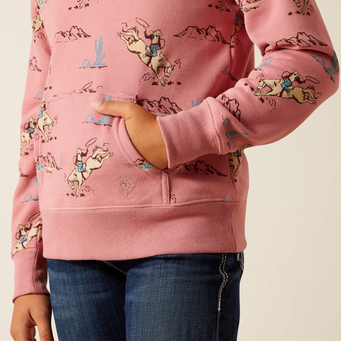 Pink kids' sweatshirt with cowboy and horse print, front pocket, paired with blue jeans