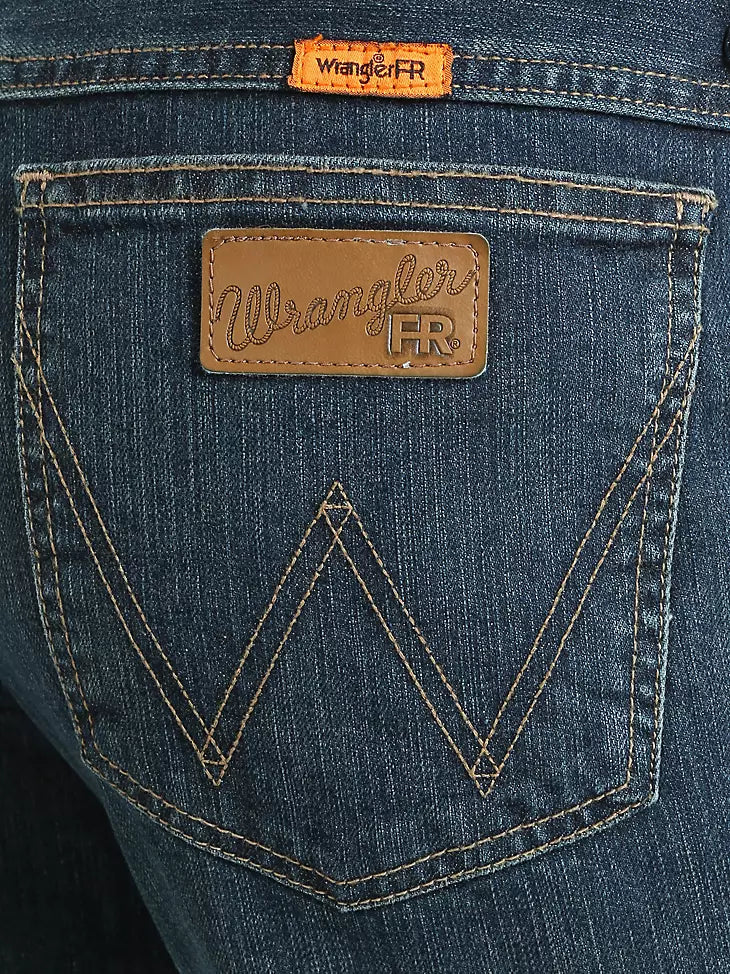 Close-up of Wrangler FR blue jeans back pocket with leather logo patch and gold stitching.