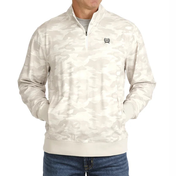 A man wearing a light beige and off-white camouflage quarter-zip pullover jacket with a small embroidered logo on the left chest, paired with blue jeans against a plain white background.