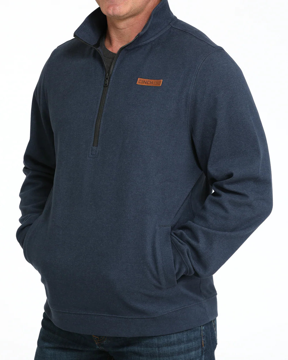 Man wearing navy blue quarter-zip pullover with pockets and brown logo patch on chest