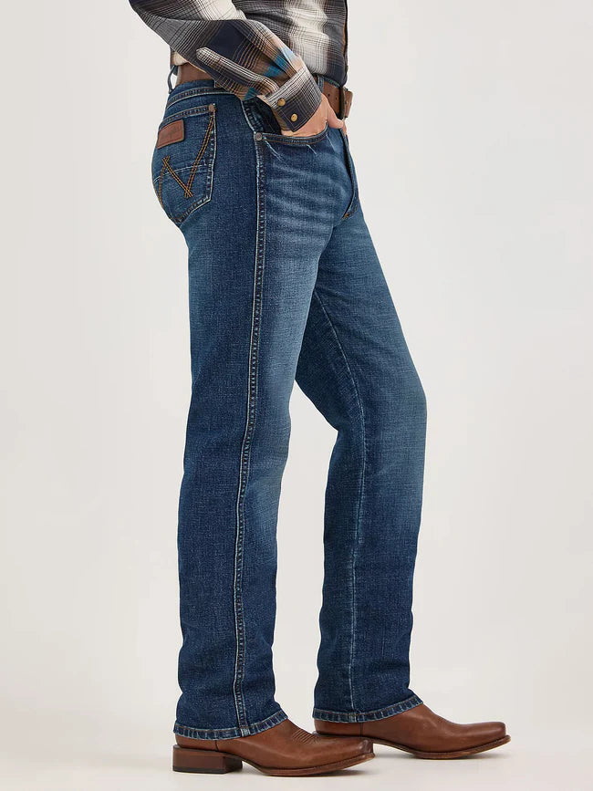 Men’s slim fit blue jeans with contrast stitching, plaid shirt, and brown leather boots