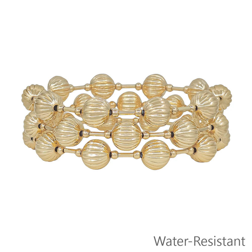Stack of gold-tone beaded bracelets with grooved round beads, water-resistant jewelry