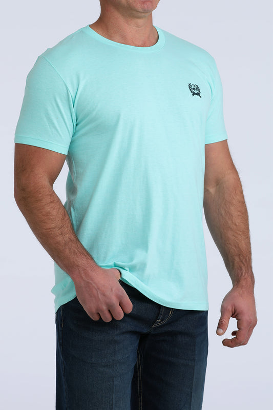 Man wearing light blue short sleeve t-shirt with small chest logo and dark jeans