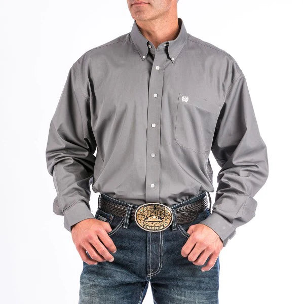 Man wearing gray button-down western shirt with chest pocket, blue jeans, and rodeo belt buckle