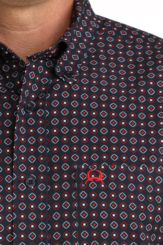 Close-up of a patterned shirt with a red logo on a dark background
