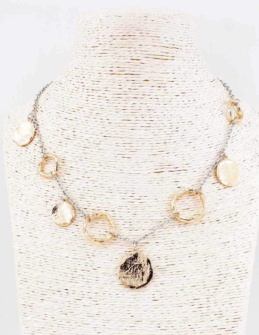 Necklace with gold and silver pendants on a textured white stand