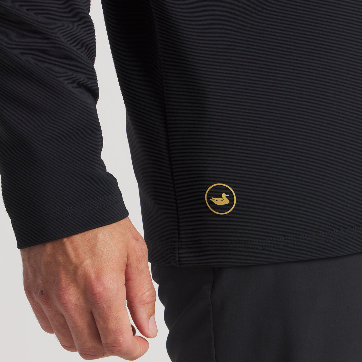 Close-up of man wearing black long sleeve outdoor shirt with small duck logo