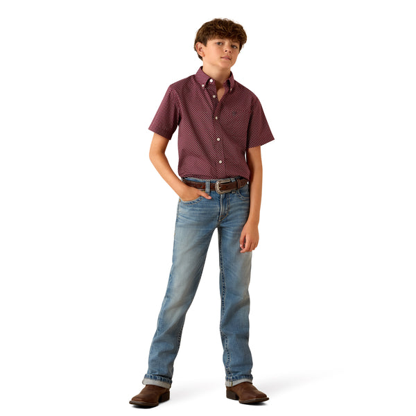 Young boy wearing a patterned shirt and jeans on a white background