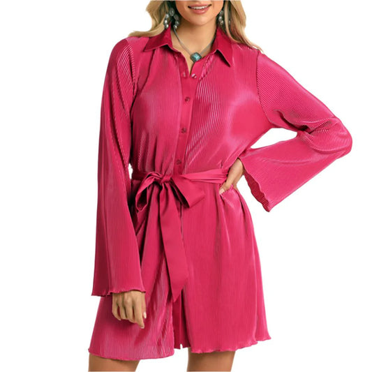 Woman wearing a hot pink plissé shirt dress with long sleeves and waist tie belt