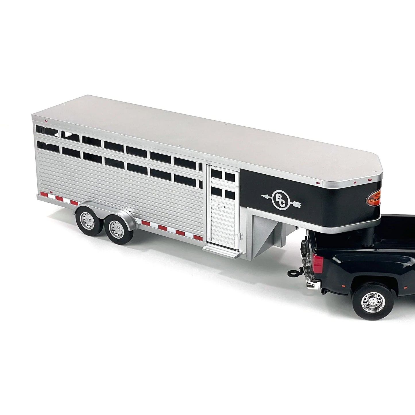 Silver gooseneck horse trailer with dual axles hitched to a black pickup truck