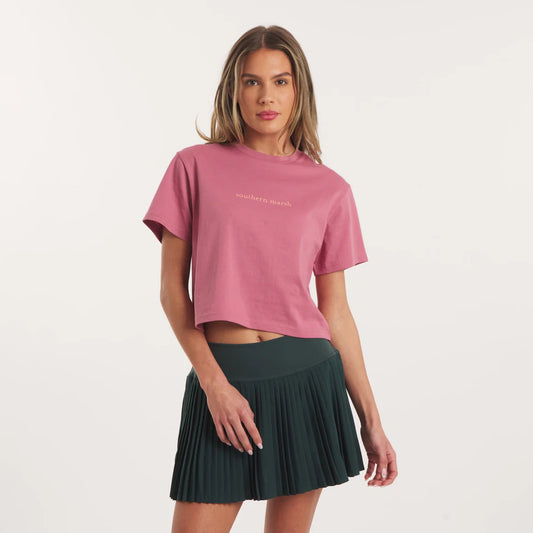 Woman wearing a pink t-shirt and green skirt on a light gray background