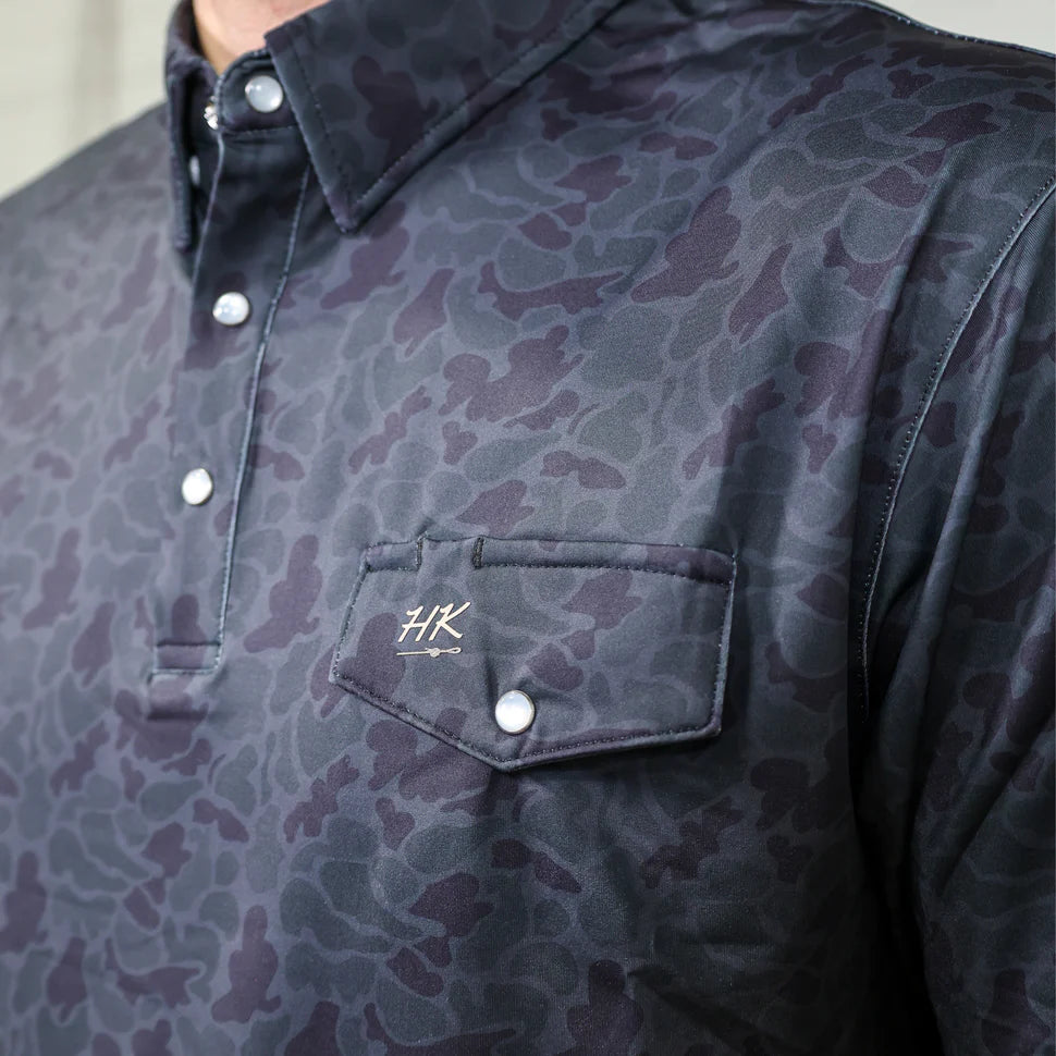 Camouflage-patterned shirt with a brand logo on a neutral background