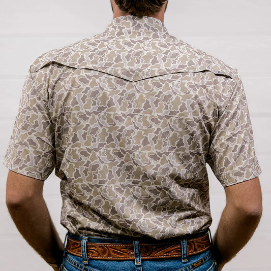 Person wearing a patterned shirt with a plain background