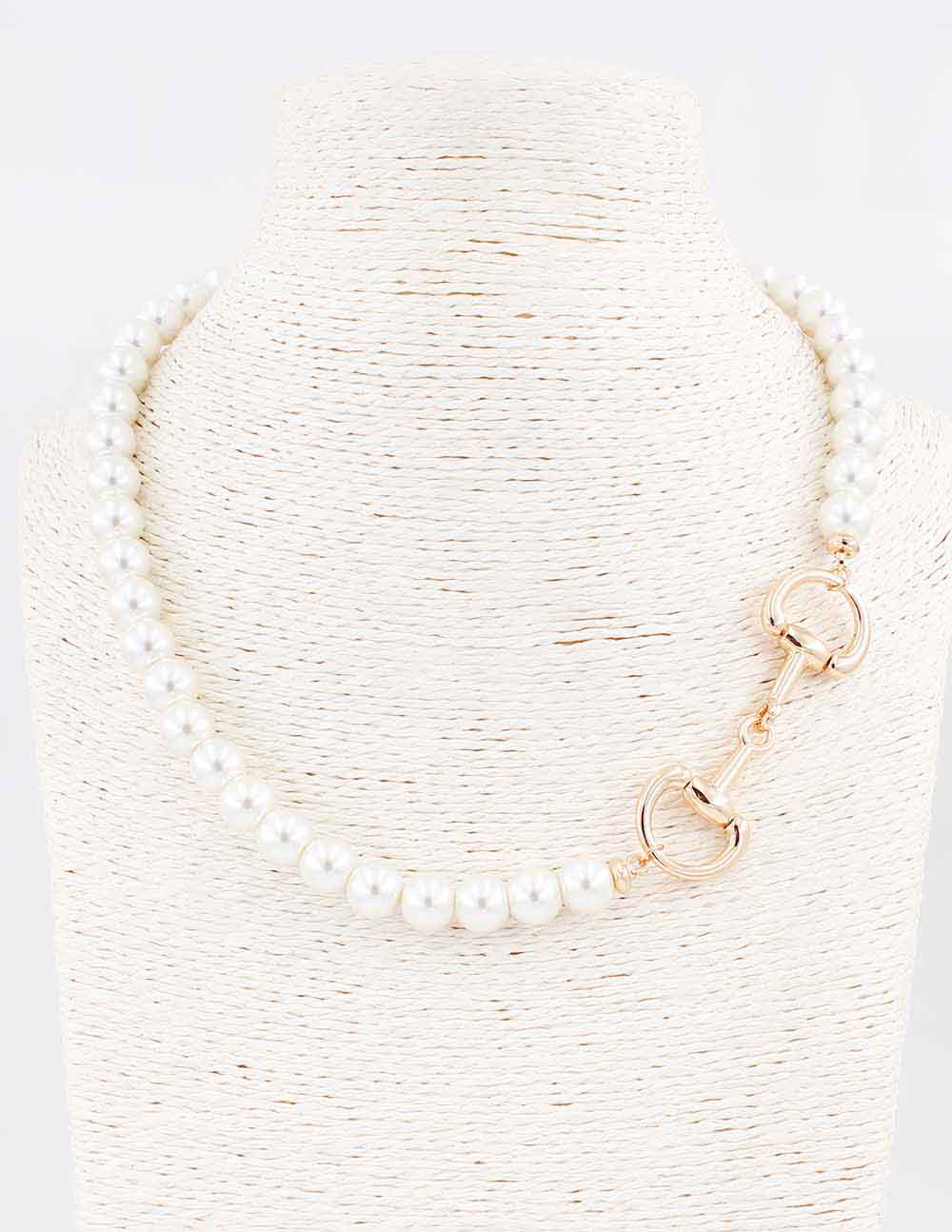 Pearl necklace with gold clasp on a textured white background