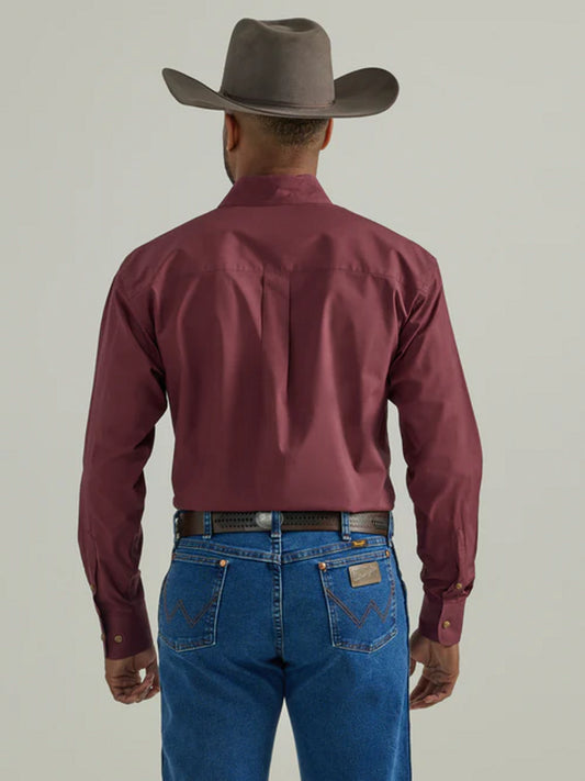 Man in maroon western shirt, blue jeans, and cowboy hat seen from behind