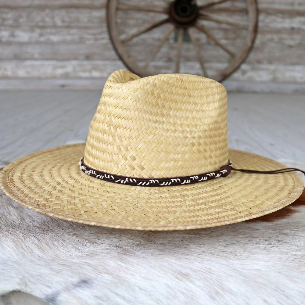Straw cowboy hat with brown and white band on rustic wood background, western accessory