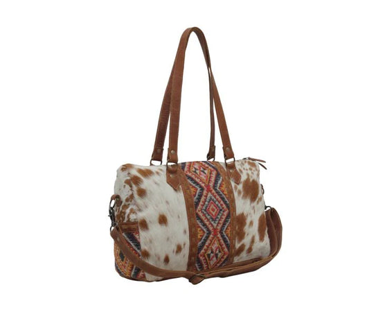 Brown and white cowhide duffel bag with tribal pattern and leather straps