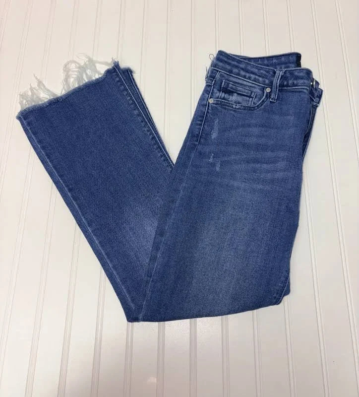 Folded blue jeans on a light wooden surface