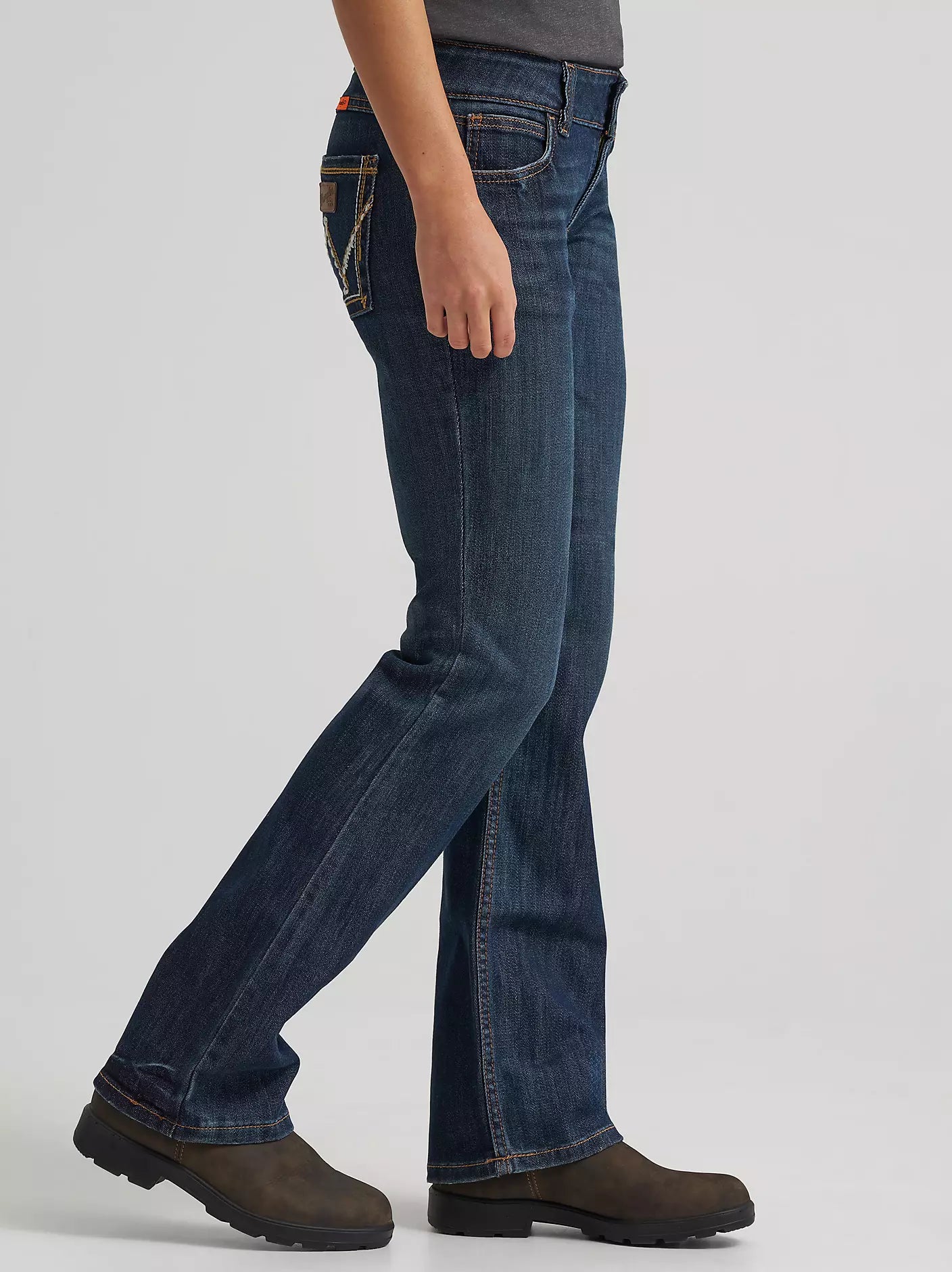 Side view of person wearing dark wash bootcut jeans and brown work boots