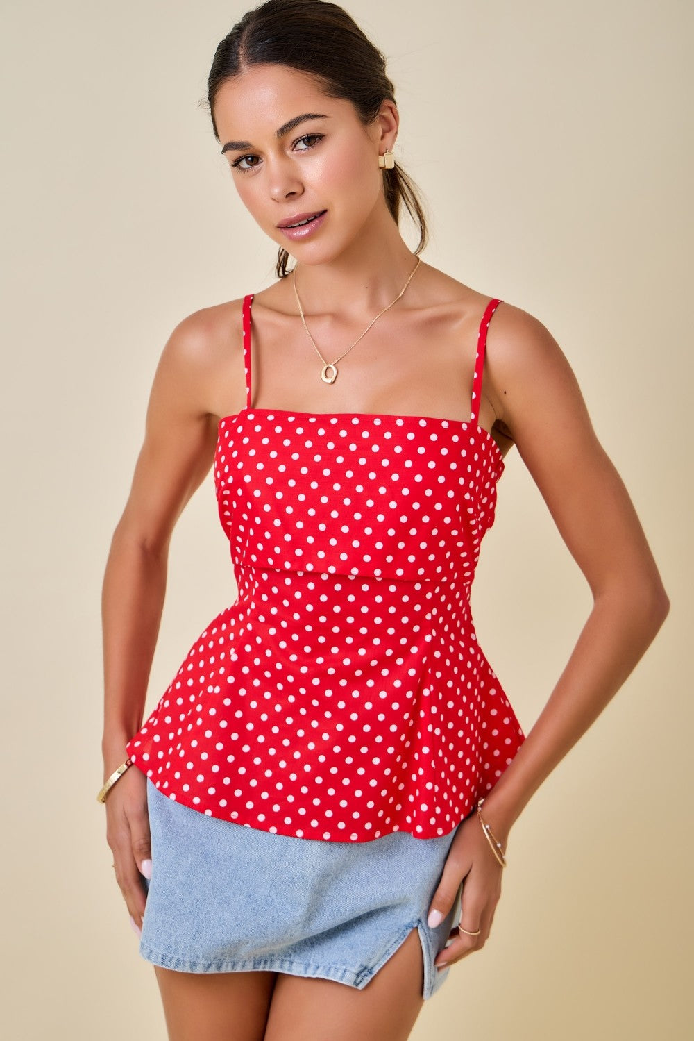 Woman wearing a red polka dot top with a beige background