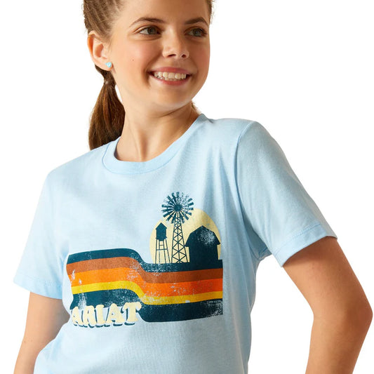 Young girl wearing a light blue t-shirt with a graphic design on a white background