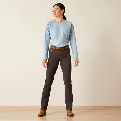 Woman wearing a light blue shirt, dark gray pants, and brown shoes on a plain background