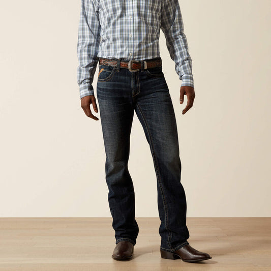 Person wearing dark blue jeans and a plaid shirt on a plain background