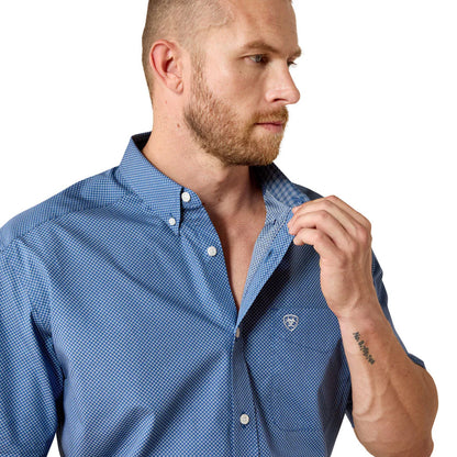 Man wearing a blue checkered shirt with a visible brand logo on a white background