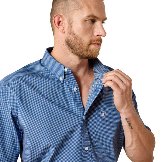 Man wearing a blue checkered shirt with a visible brand logo on a white background