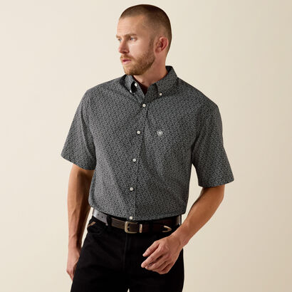 Man wearing a patterned short-sleeve shirt against a beige background