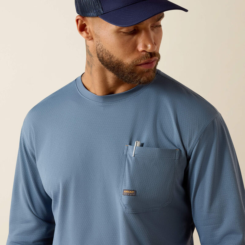 Man wearing blue long sleeve utility shirt with chest pocket and pen, navy mesh cap