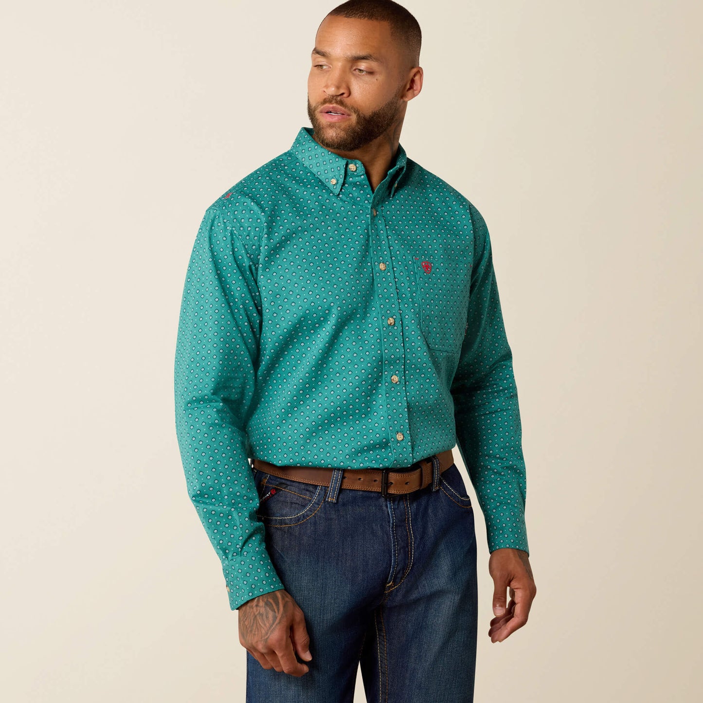 Man wearing teal patterned long-sleeve button-up shirt and blue jeans