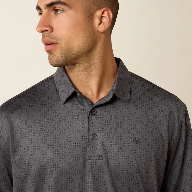 Man wearing a gray patterned polo shirt against a beige background