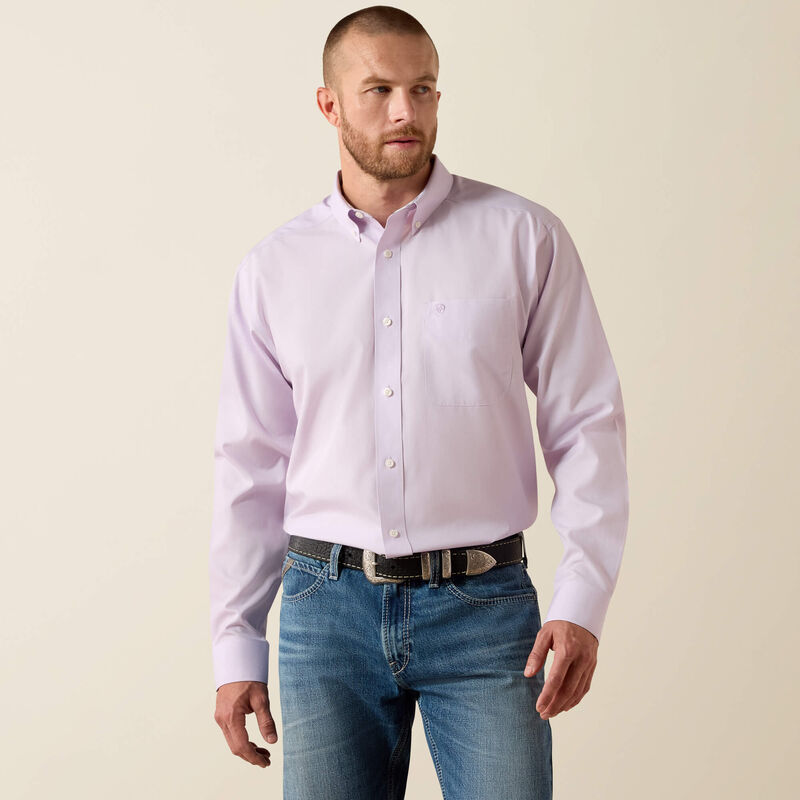 Man wearing a light purple button-up shirt and blue jeans on a beige background