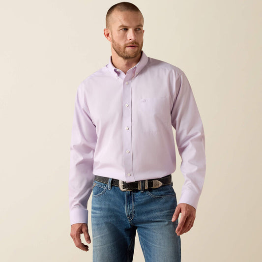 Man wearing a light purple button-up shirt and blue jeans on a beige background