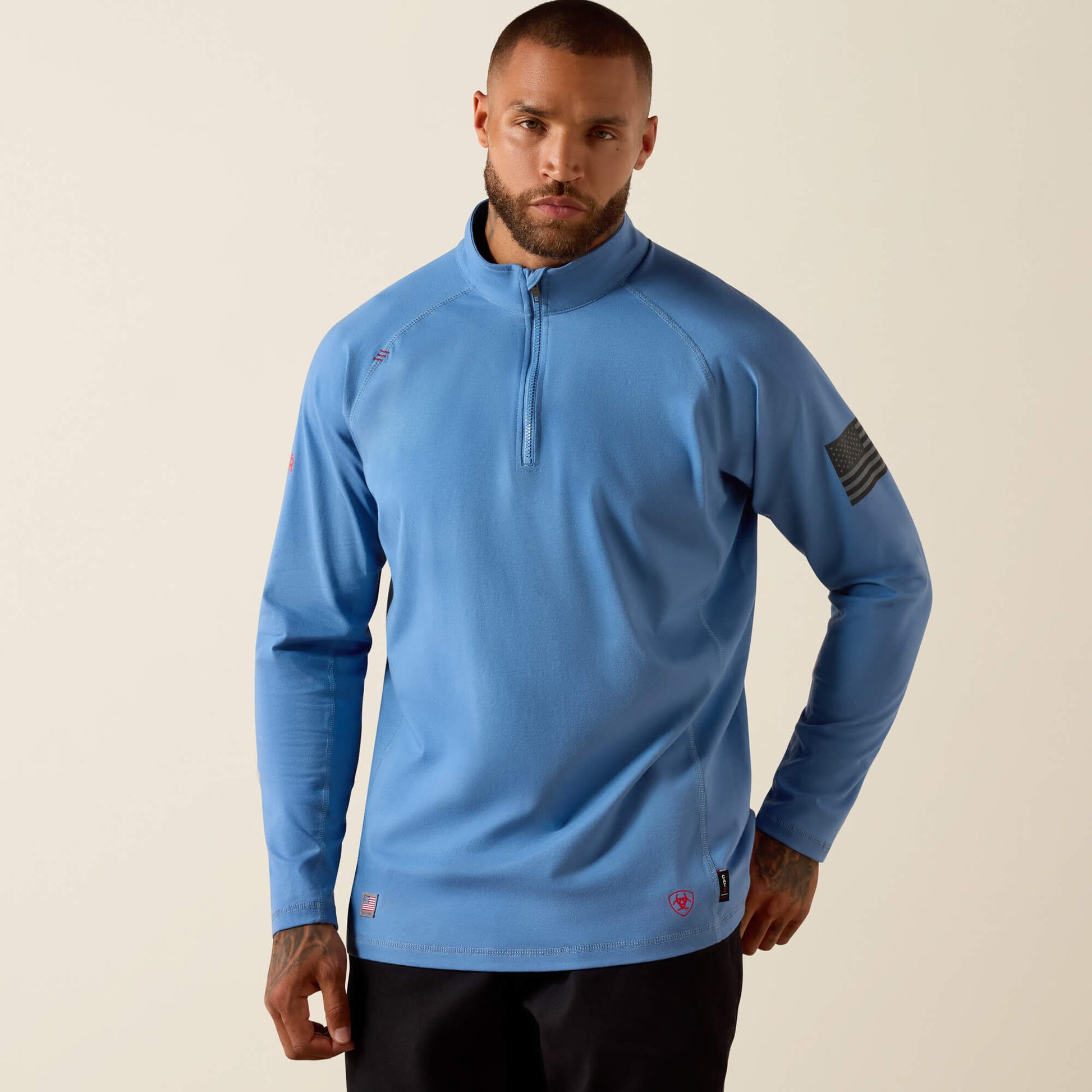 Man wearing light blue long sleeve quarter-zip pullover with American flag patch on sleeve