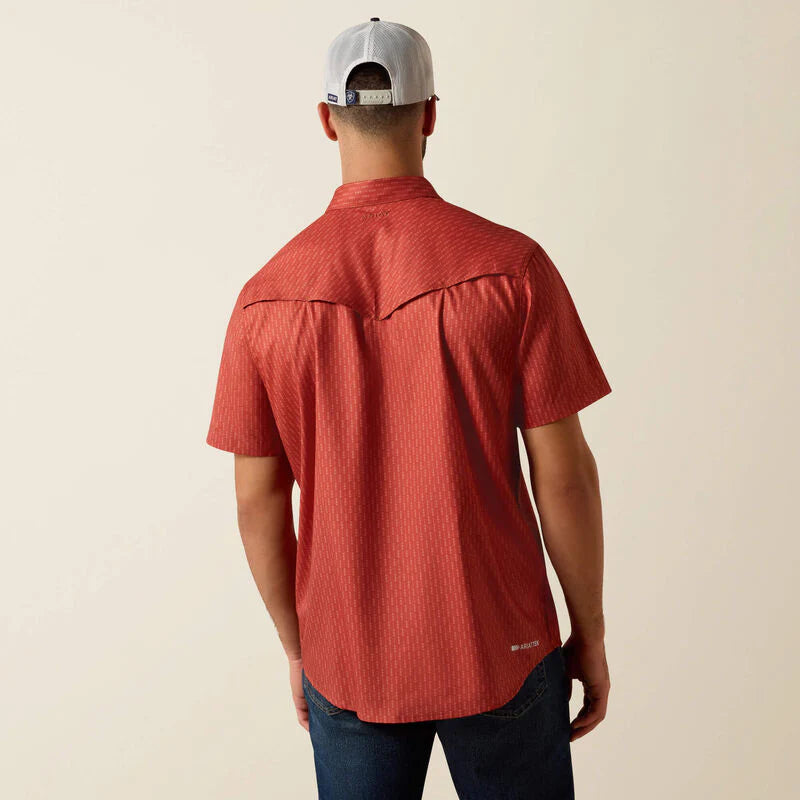 Person wearing a red short-sleeve shirt and a cap on a beige background