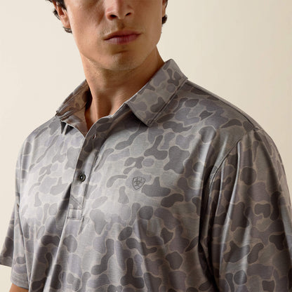 Man wearing a camouflage-patterned polo shirt against a neutral background
