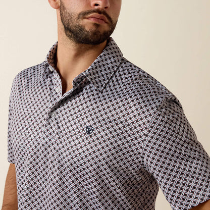 Man wearing a patterned shirt against a beige background
