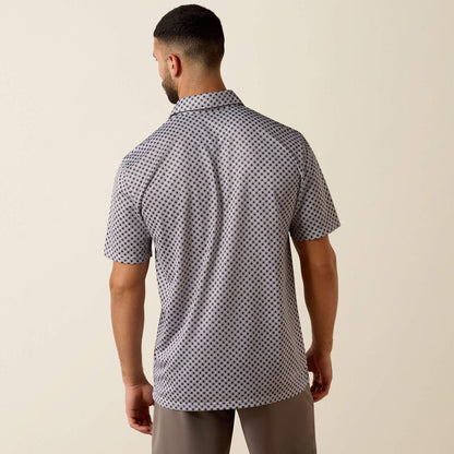 Man wearing a patterned short-sleeve shirt against a beige background
